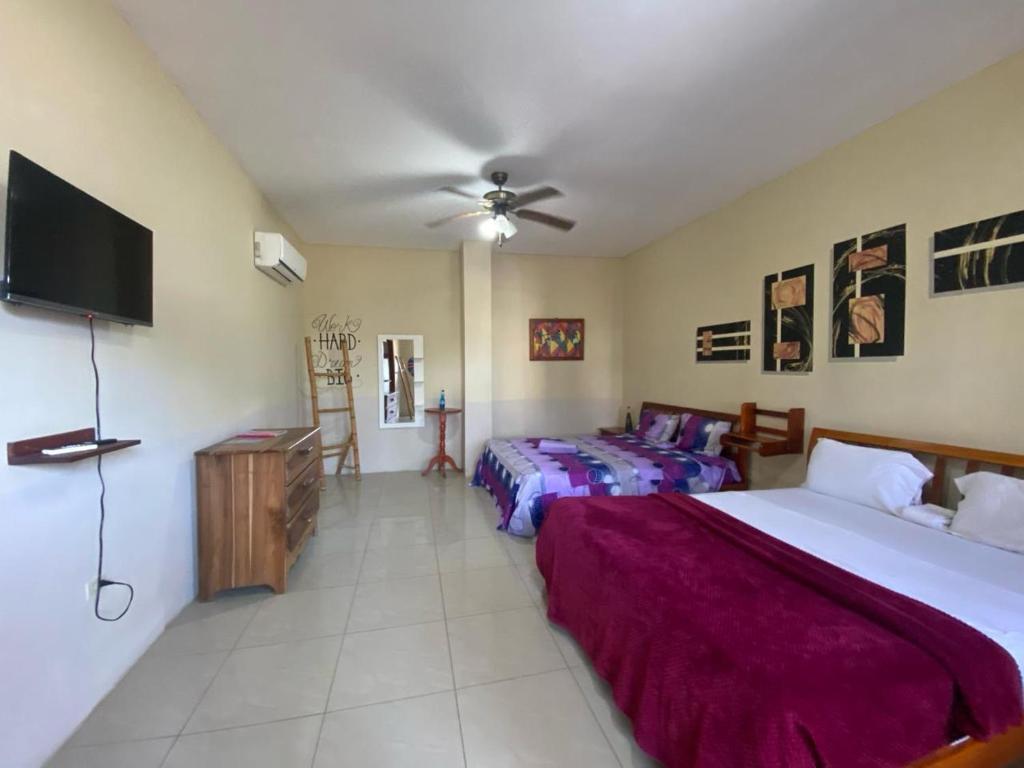 a bedroom with two beds and a flat screen tv at Hotel MAHAI in Olón
