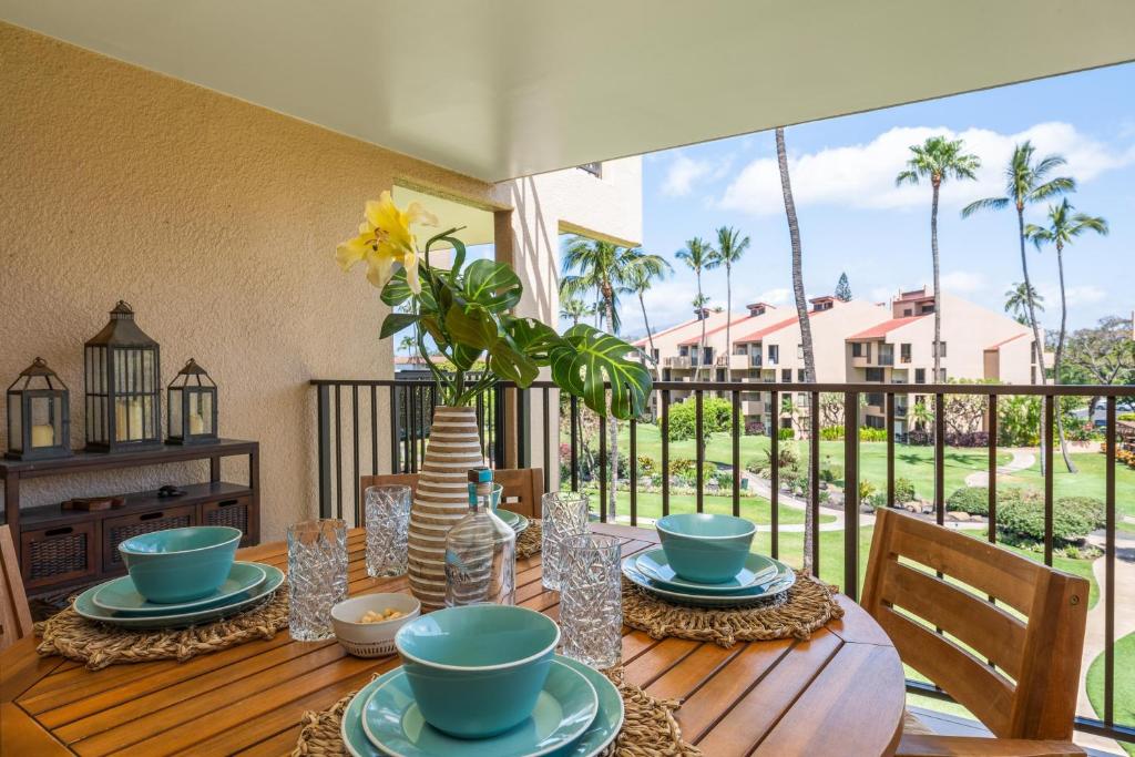 a table with plates and bowls on top of a balcony at Kamaole Sands 7307 in Wailea