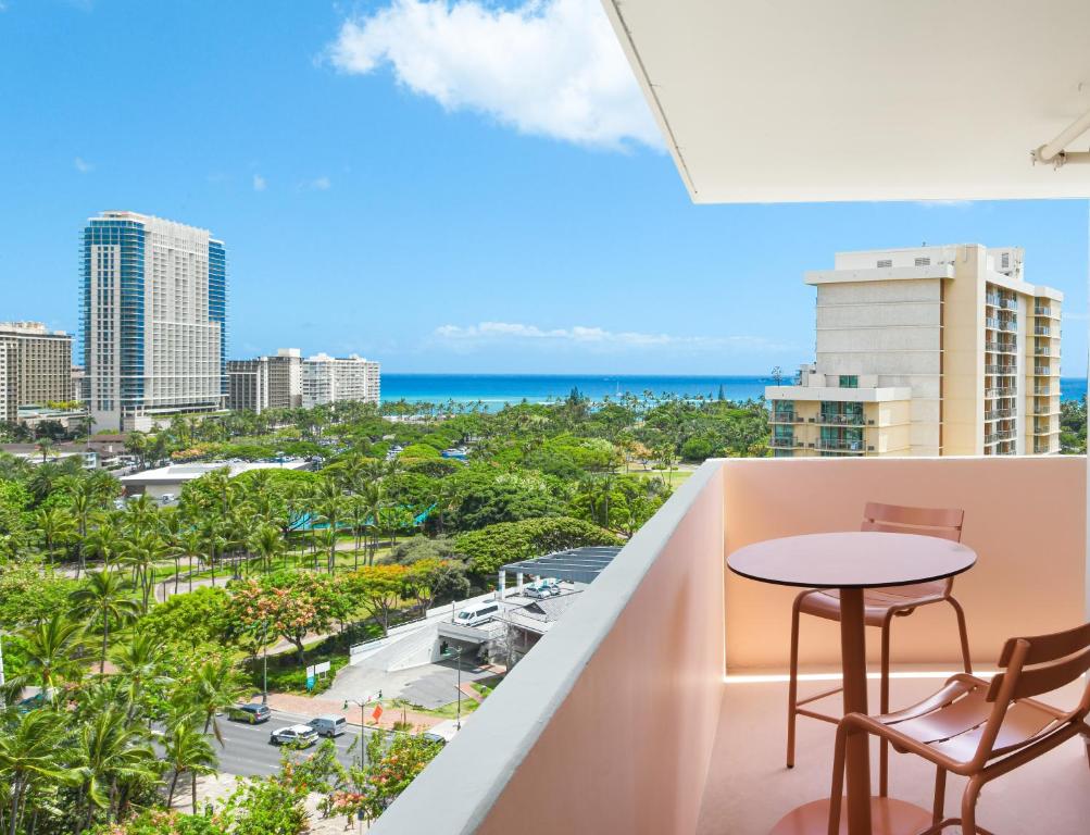 uma varanda com uma mesa e cadeiras e o oceano em Romer Waikiki at The Ambassador em Honolulu