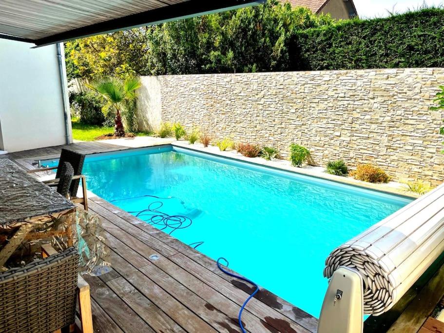 una piscina in un cortile con terrazza in legno di Maison au cœur des châteaux de la Loire a La Chaussée-Saint-Victor