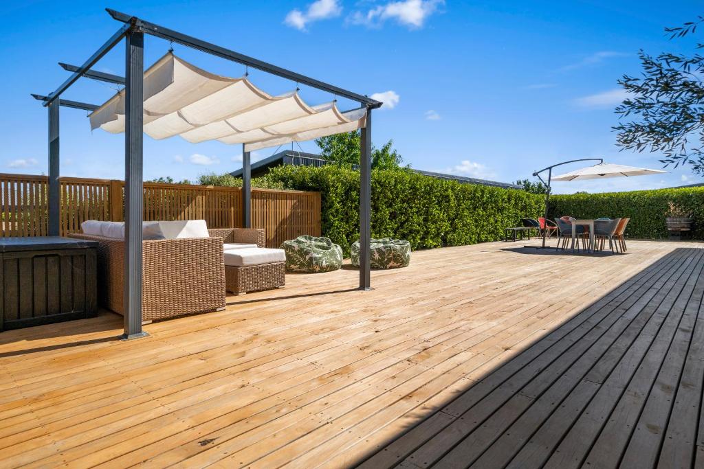 een houten terras met een pergola en een tafel en stoelen bij House Naomi - Martinborough Holiday Home in Martinborough 