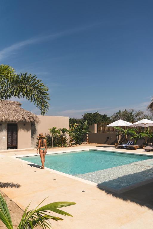 a woman in a bikini walking by a swimming pool at La Barra Resorts Puerto Escondido in Puerto Escondido