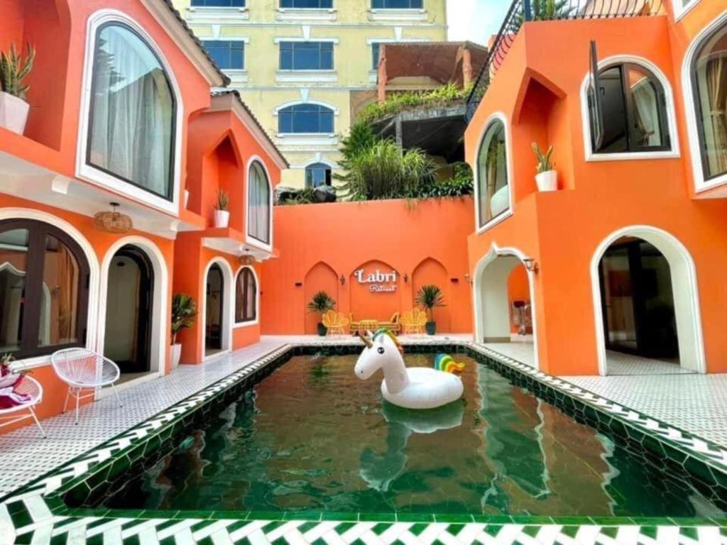 un edificio naranja con una piscina con un unicornio. en L’abri Retreat _ Venuestay, en Tam Ðảo