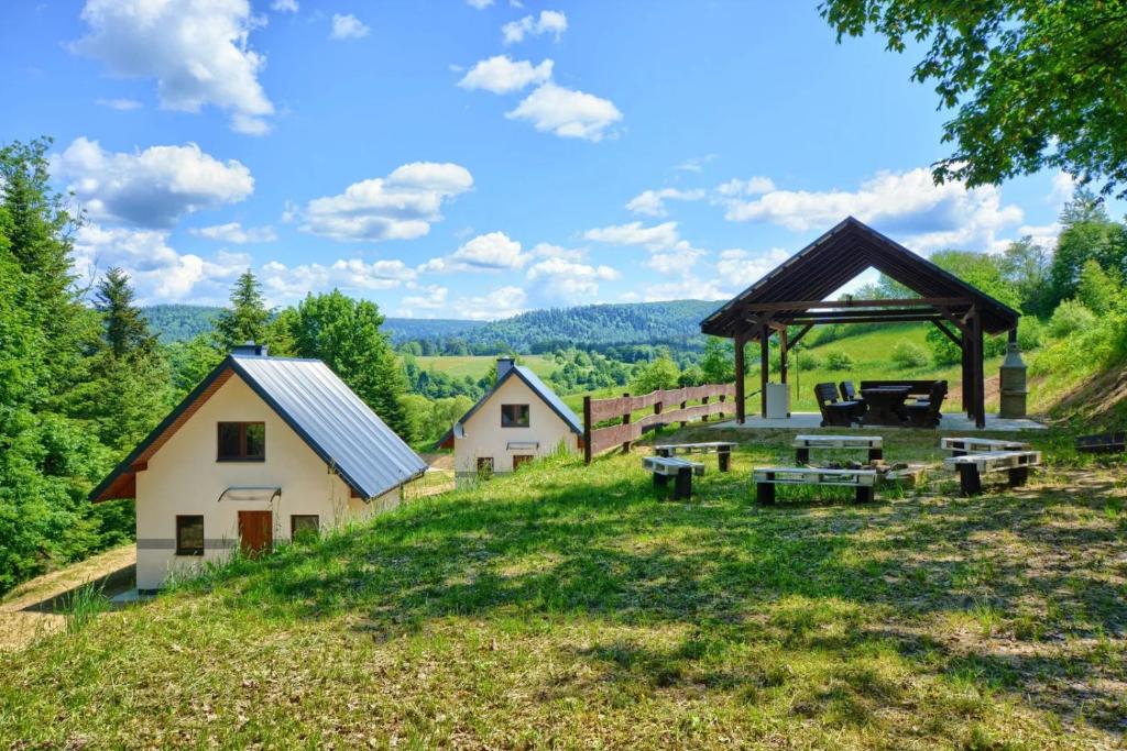 eine Gruppe von Häusern auf einem Hügel mit einem Picknicktisch in der Unterkunft Domki Potok - Noclegi Bieszczady in Stefkowa