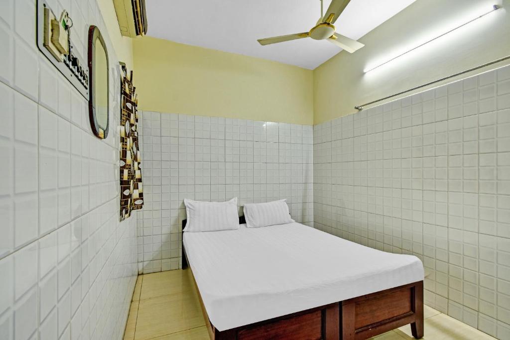 a room with a bed in a cell with white tiles at OYO 86379 Dream Palace Guest House Near Marina Beach in Chennai