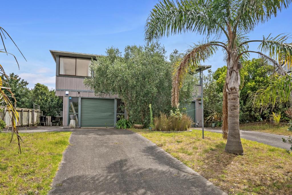 une maison avec un palmier et une allée dans l'établissement Relax on Queens - Waikanae Beach Holiday Home, à Waikanae