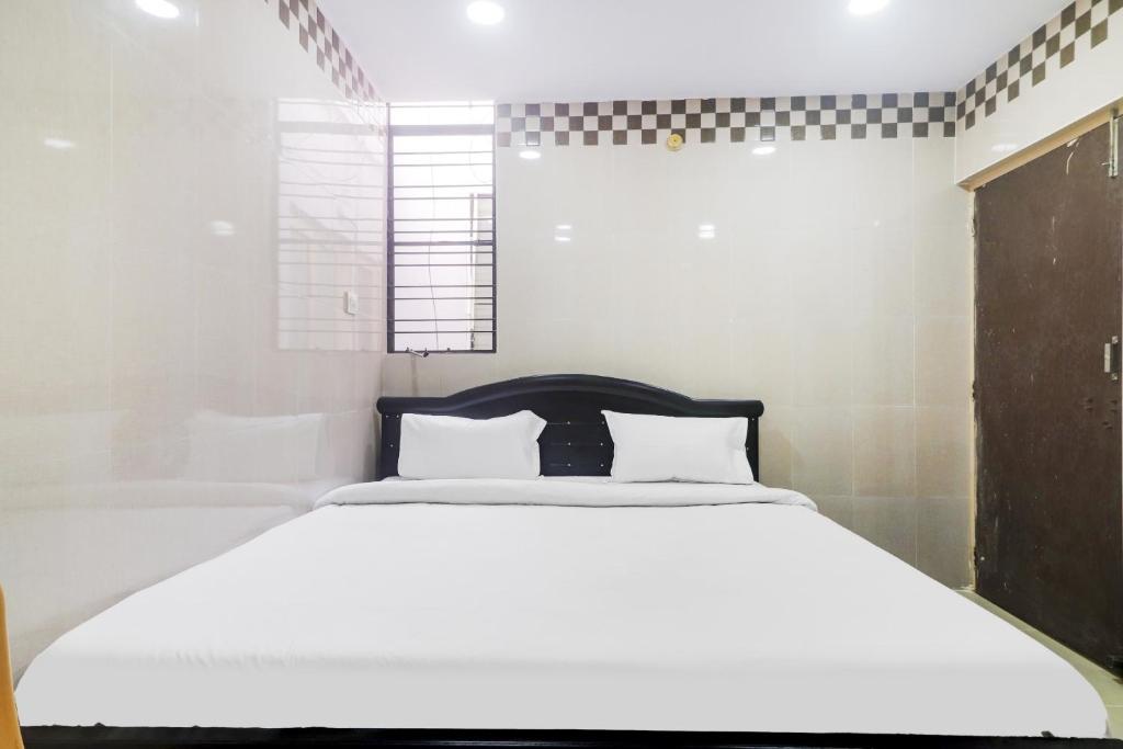 a bedroom with a white bed and a window at OYO Hotel Aroma Classic Near Nampally Railway station in Hyderabad