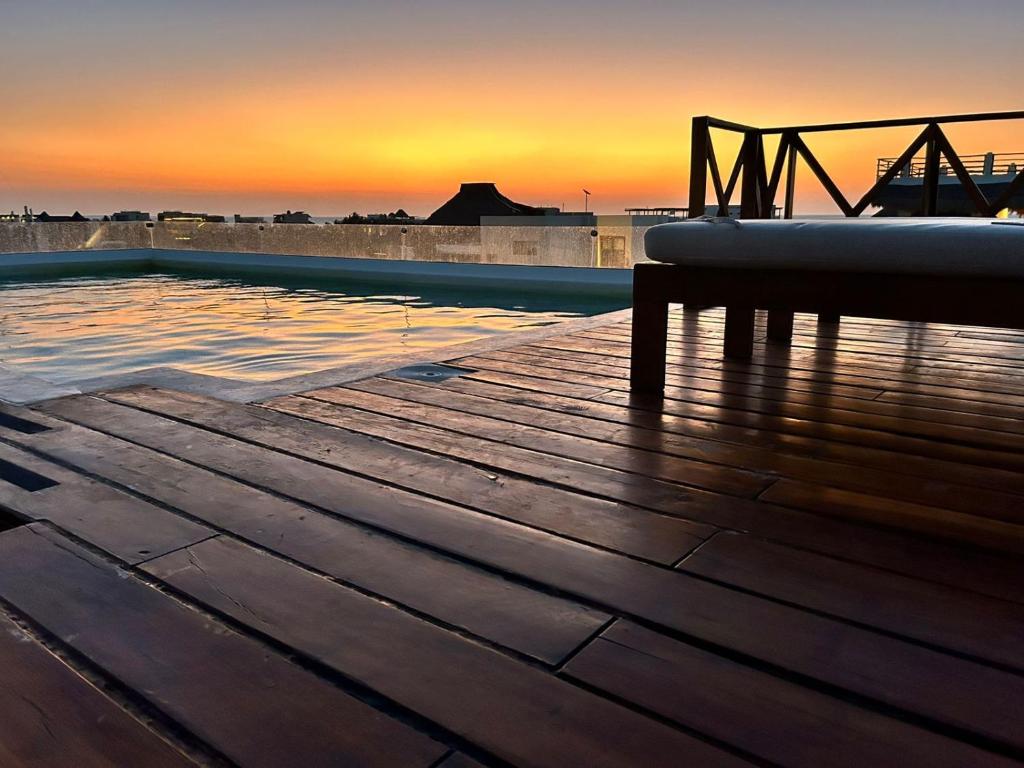 uma piscina com um banco num deque com o pôr-do-sol em Sunsteps suite pyramids em Holbox