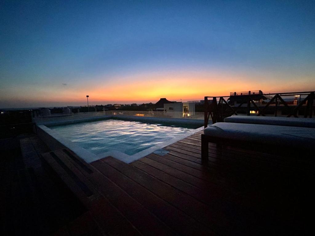 - une piscine au-dessus d'un immeuble avec vue sur le coucher du soleil dans l'établissement sunsteps green falls, à Holbox
