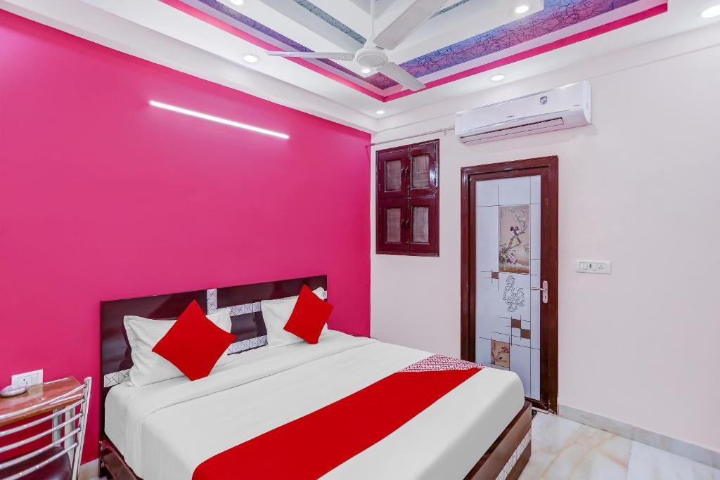 a pink bedroom with a bed with red pillows at Super OYO The Prima Residency in Ghaziabad
