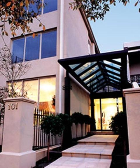 a large white building with glass windows and a porch at Knightsbridge Apartments in Melbourne
