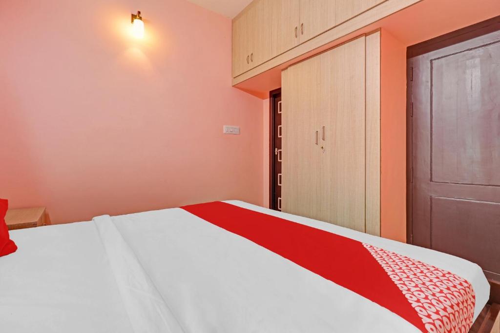 1 dormitorio con 1 cama con manta roja y blanca en Highways Residency, en Madurai