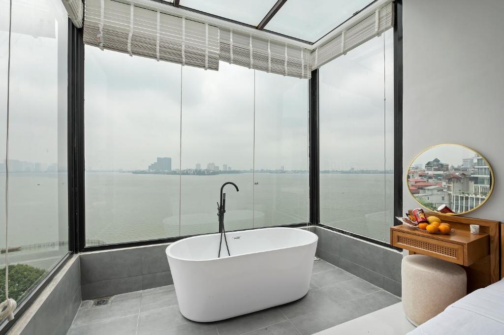 a bath tub in a room with large windows at Lakeview Residence Hotel in Hanoi