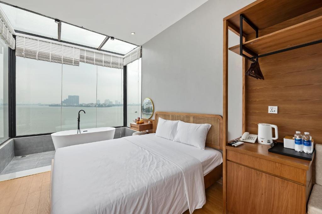 1 dormitorio con cama y bañera junto a una ventana en Lakeview Residence Hotel, en Hanói