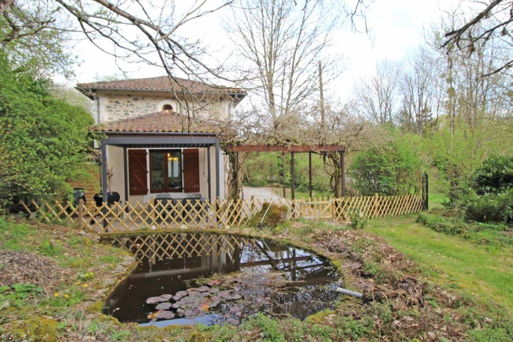 una pequeña casa con un puente sobre un estanque en Le vieil orme en Saint-Junien
