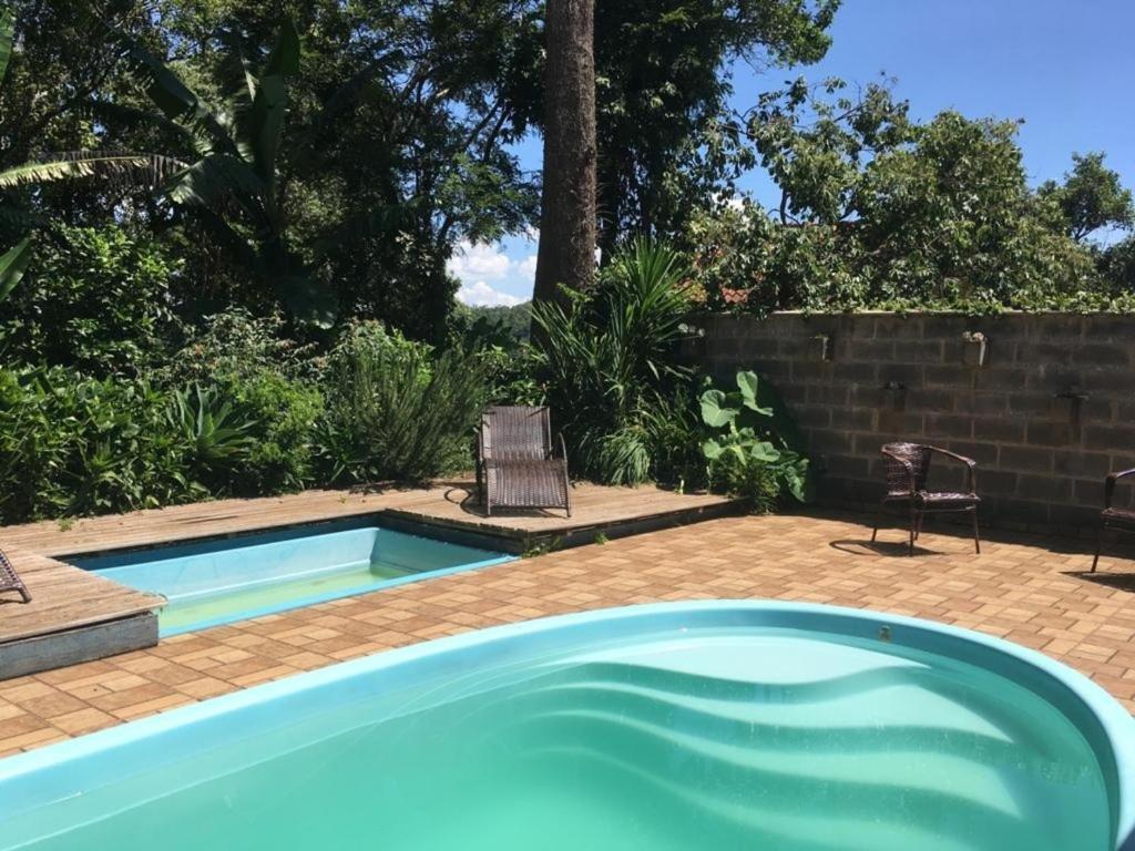 uma piscina num quintal com duas cadeiras ao lado de uma parede em Ninho da Águia; Espetáculo da natureza em Poços de Caldas