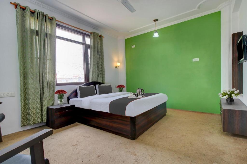 a bedroom with a large bed and a green wall at Capital O Yasmin Resort in Baghwānpur