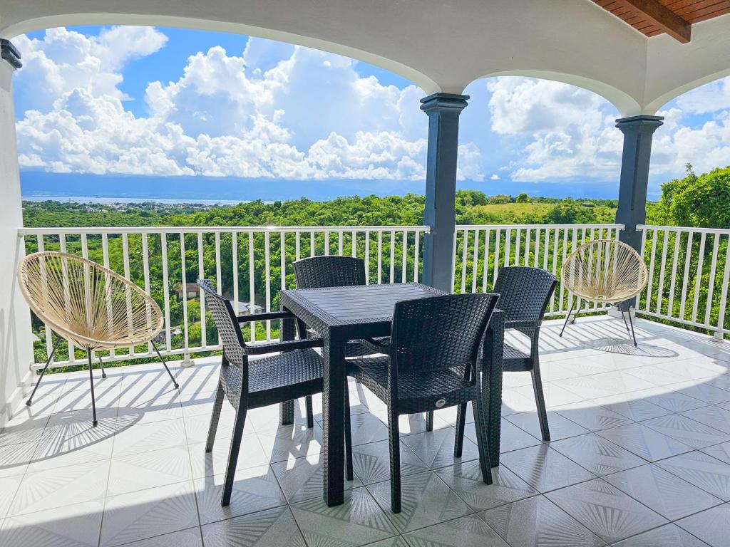 eine Terrasse mit einem Tisch und Stühlen auf dem Balkon in der Unterkunft Maison (Vu sur le Lagon) in Le Gosier