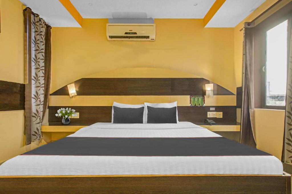 a bedroom with a large bed with yellow walls at Super Collection O Mgr Inn in Puducherry