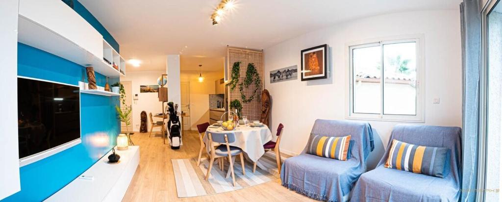 瑞維尼亞克的住宿－La palmeraie - Piscine vue golf，客厅配有2把蓝色椅子和桌子