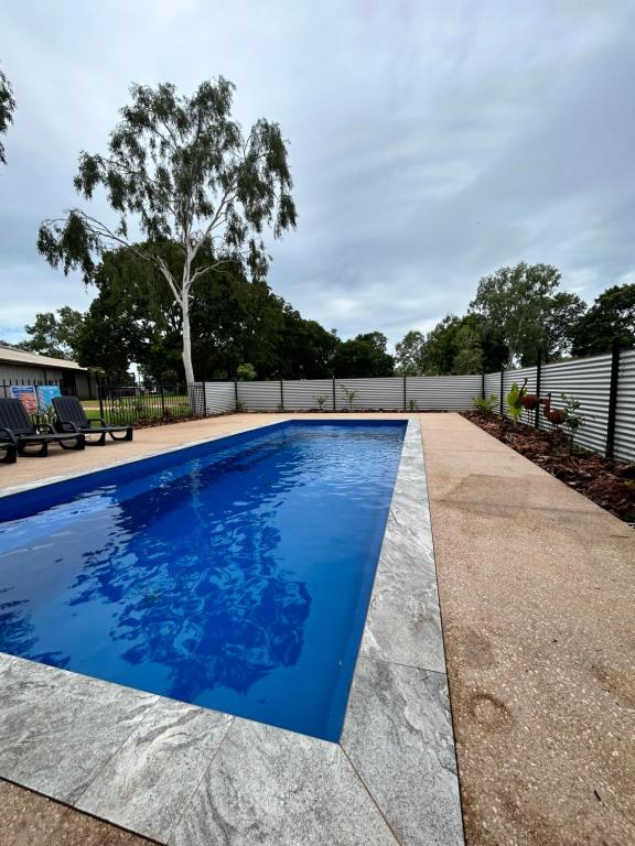 a swimming pool with blue water in a yard at Katherine Farmstay Caravan Park in Katherine