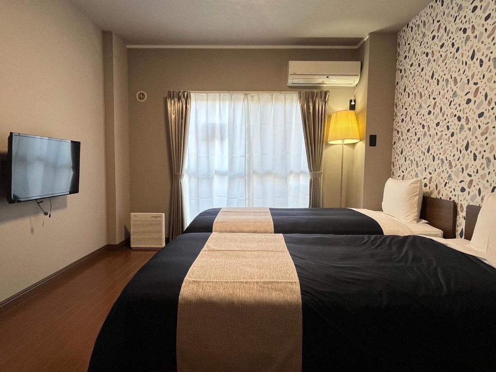 a hotel room with two beds and a television at Stay Airport in Fukuoka