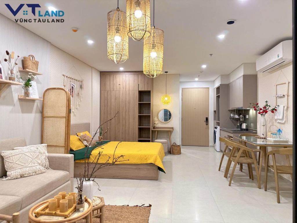 1 dormitorio con 1 cama amarilla y cocina en The Sóng Hotel & Apartment Vũng Tàu - VTLand, en Vung Tau