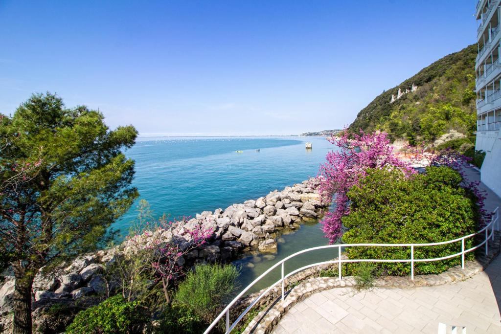 a walkway next to a body of water with flowers at Residence Europa in Sistiana