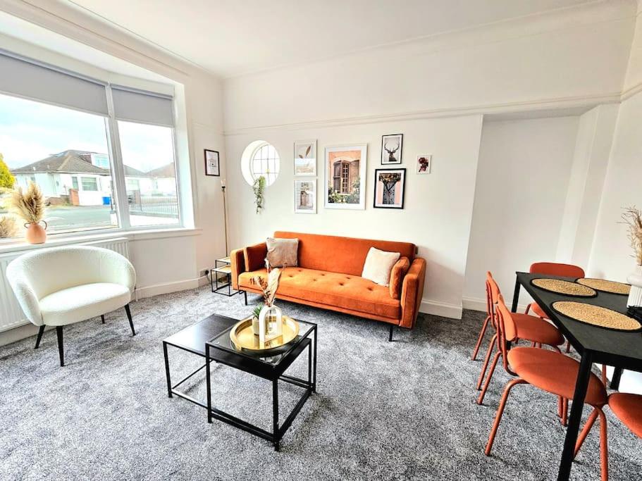 Charming 3-Bed Oasis-free parking في غلاسكو: غرفة معيشة مع أريكة برتقالية وطاولة