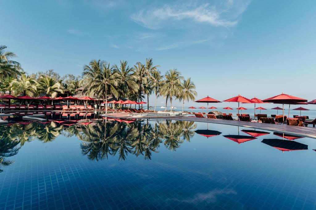 una piscina con ombrelloni e sedie e un resort di Khaolak Laguna Resort a Khao Lak