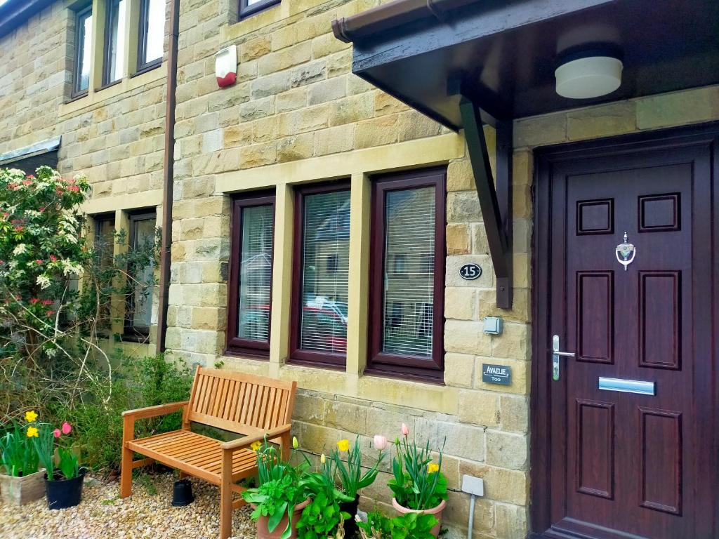 a wooden bench next to a building with a door at Avaelie Too in Hebden Bridge