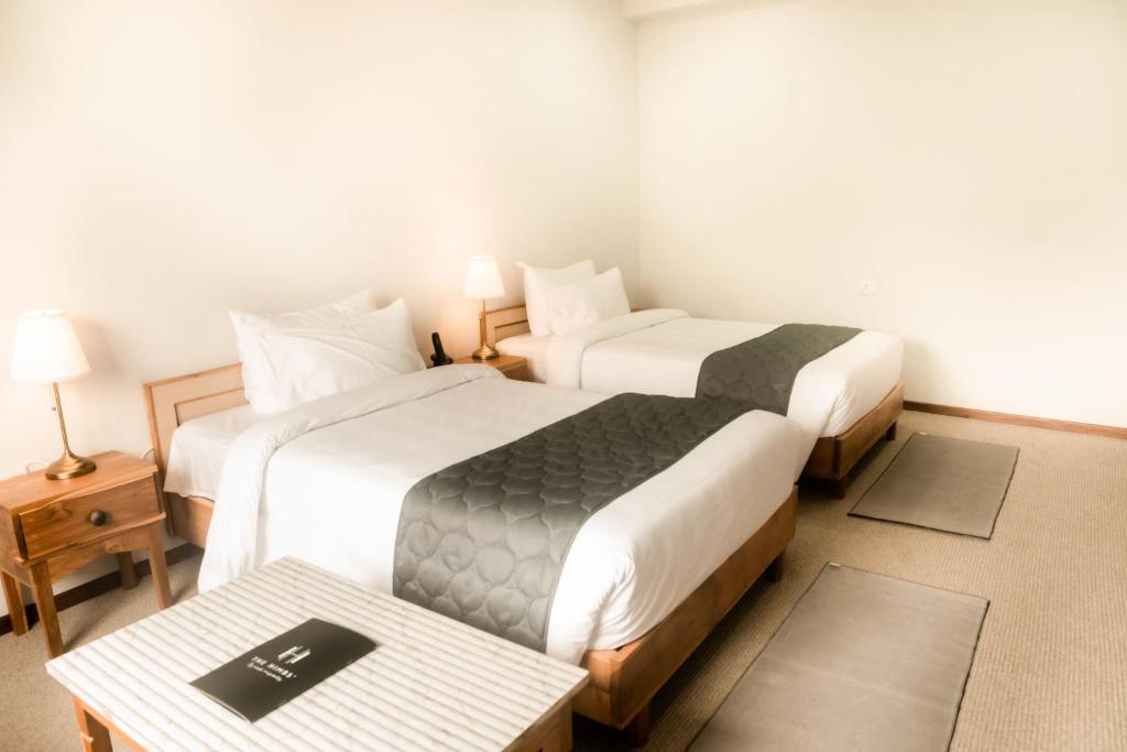 ディマプルにあるTHE HIMBS HOTELのベッド2台とテーブルが備わるホテルルームです。