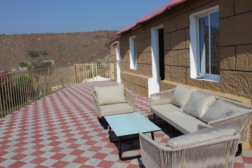 a patio with a couch and chairs on a checkered floor at Hatta Hills in Al Ḩajarayn