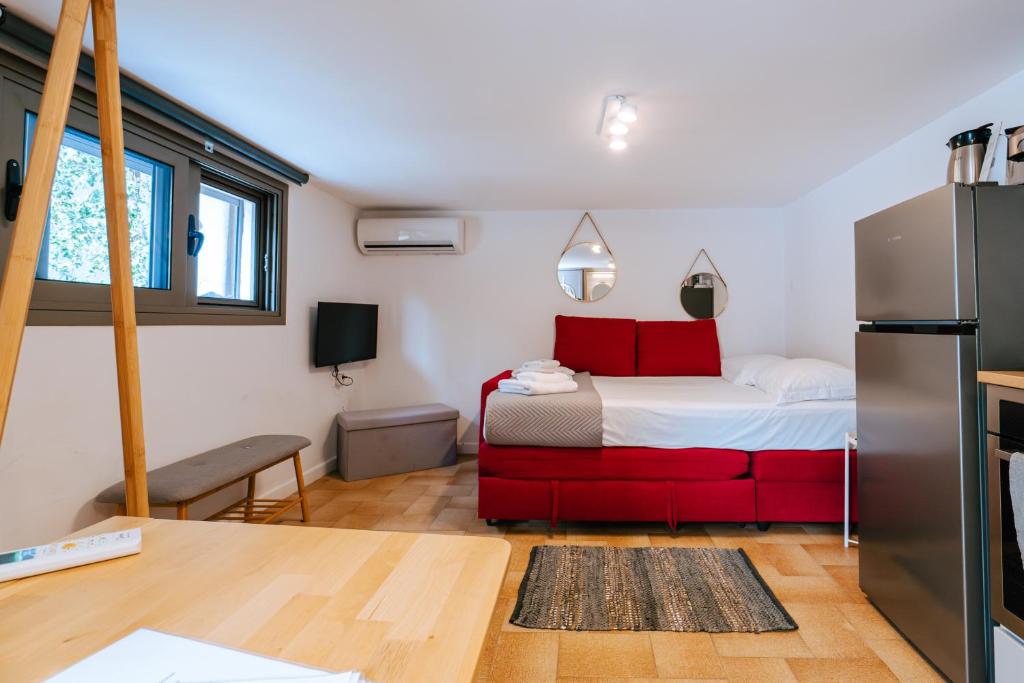 Habitación pequeña con cama roja y nevera. en Sibylla Studio Deluxe, en Kalymnos