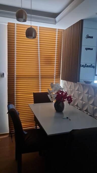 a dining room table with a vase of flowers on it at Apartament litoral norte NatalRN in Natal