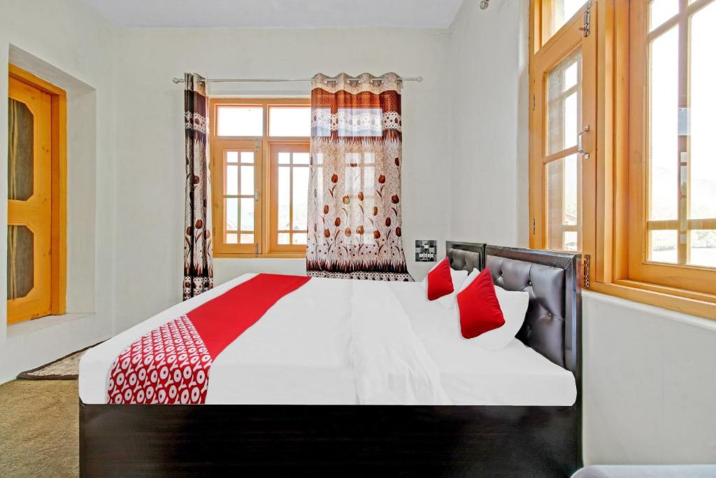 a bedroom with a large bed with red pillows at OYO Green Resort in Gandbal