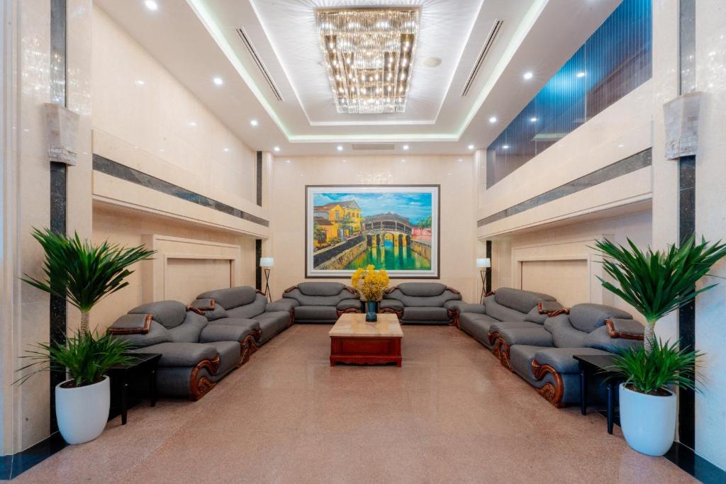 A polished hotel lounge is arranged with grey sofas, plants, and a central coffee table.
