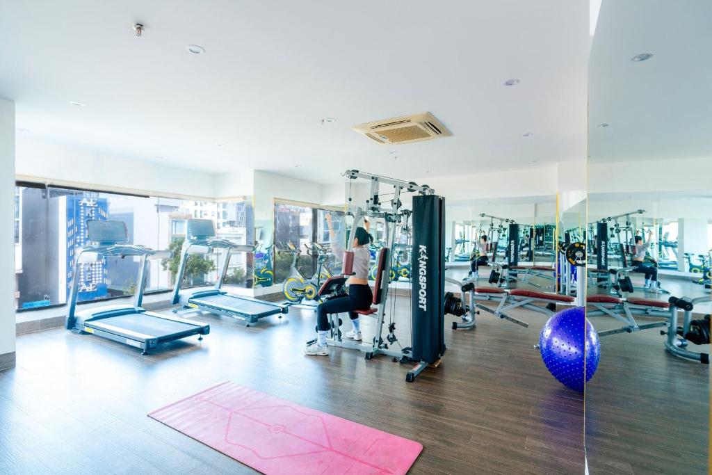 A sunny mirrored gym with treadmills, a cable machine and a pink exercise mat.