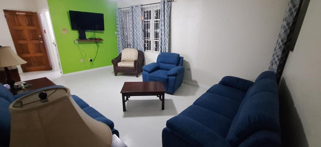 a living room with a blue couch and chairs at Seaview Property 1C Two Bedroom Apt Hasting Towers in Bridgetown