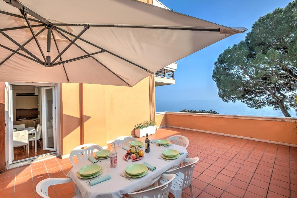 una mesa con sillas y una sombrilla en el patio en Franka House Fantastic Lake View - Happy Rentals, en Gardone Riviera