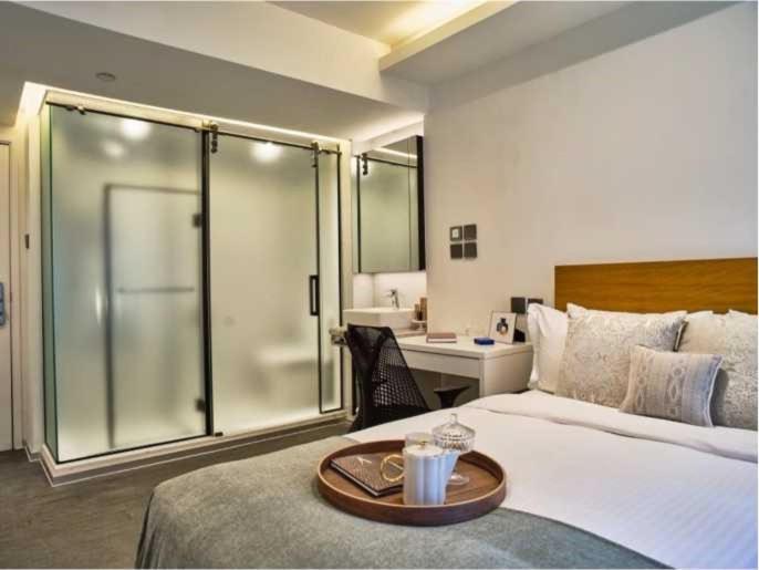 ein Hotelzimmer mit einem Bett und einer Glasdusche in der Unterkunft V Causeway Bay in Hongkong