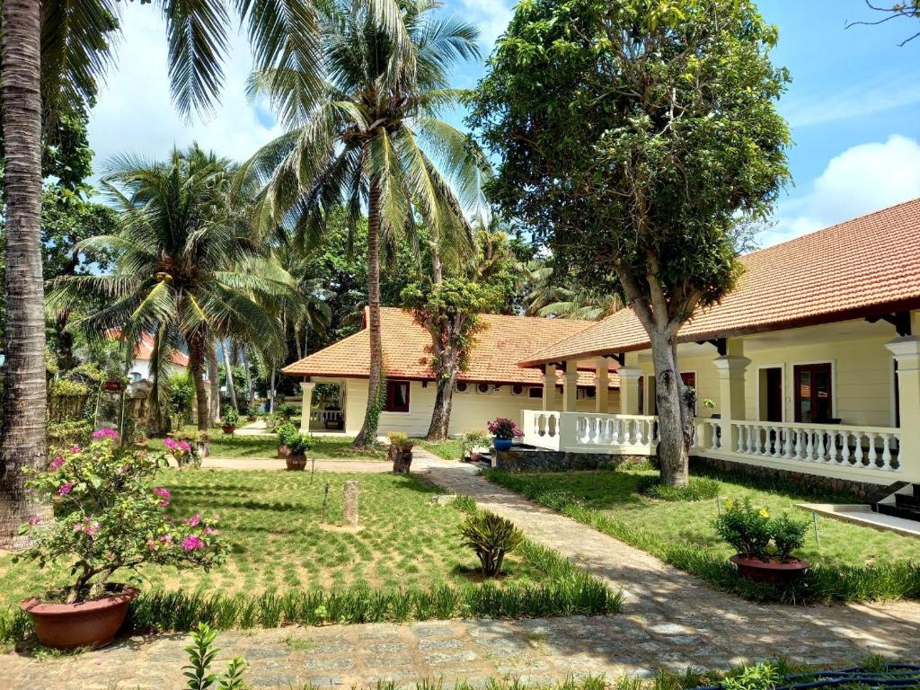 een huis met een tuin en palmbomen bij Sài Gòn Côn Đảo Resort in Con Dao