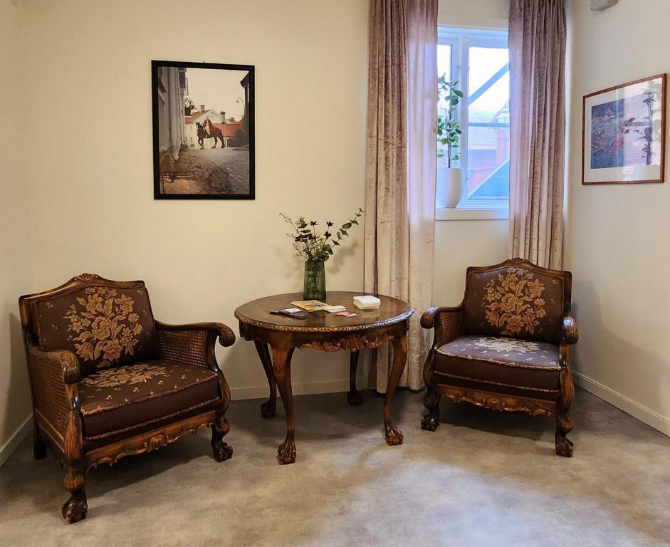a living room with two chairs and a table and a table and chairs at Vandrarhemmet Garvaren gamla stan Eksjö in Eksjö