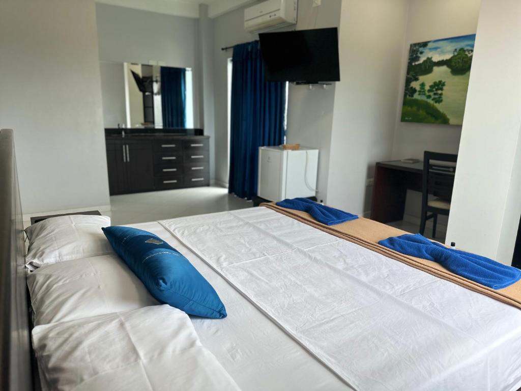 uma grande cama branca com almofadas azuis num quarto em Hotel Cristo rey em Tabatinga