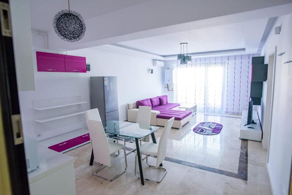 un soggiorno con tavolo in vetro e divano rosa di Sophia 2 & Moonlight Apartaments a Mamaia