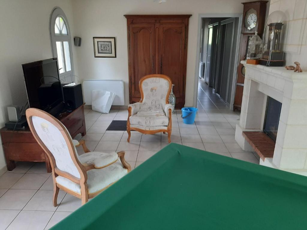 - un salon avec une table, 2 chaises et une cheminée dans l'établissement Au chêne vert, à Saumur