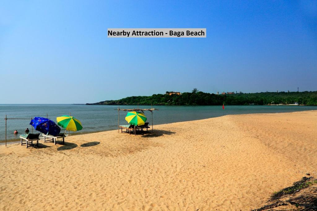 two beach chairs with umbrellas on a sandy beach at OYO Royal Castle Near Baga Beach in Baga