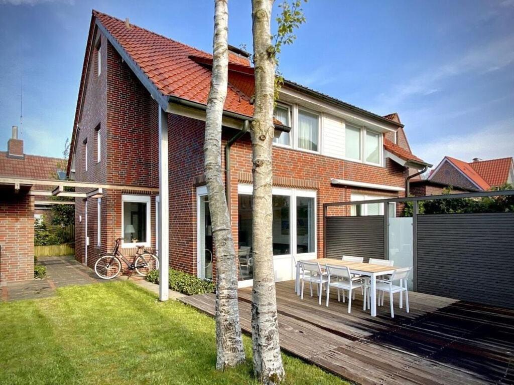 a house with a wooden deck with a table in the yard at Christel Modern retreat in Langeoog