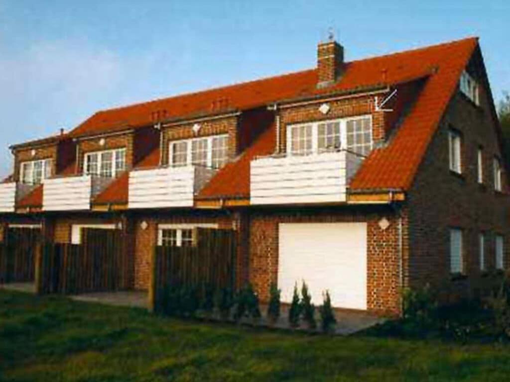 una gran casa de ladrillo con dos puertas blancas de garaje en to FEEL GOOD Modern retreat, en Dornumersiel