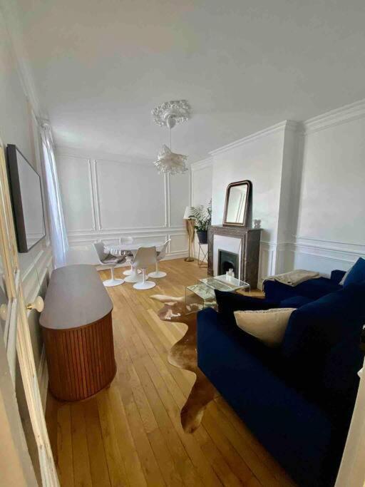un salon avec un canapé bleu et une table dans l'établissement Superbe appartement avec moulures et cheminé, à Clichy